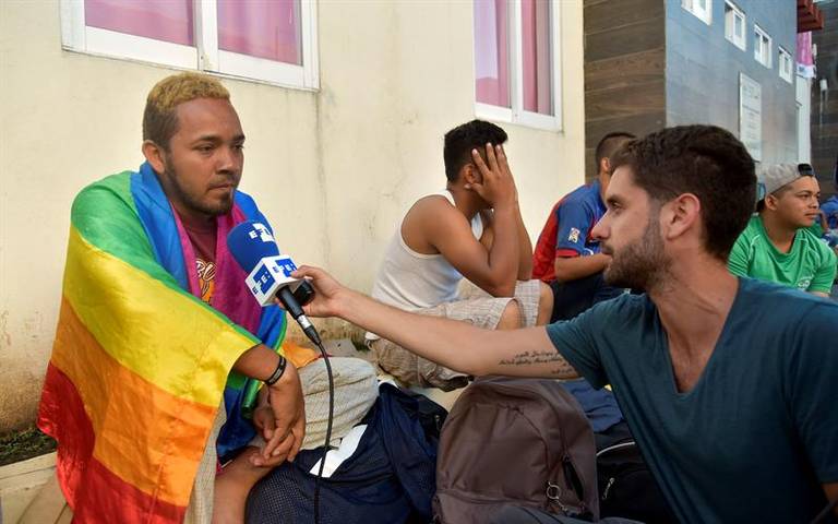 Migrante gay lleva la bandera del orgullo manchada de miedo y